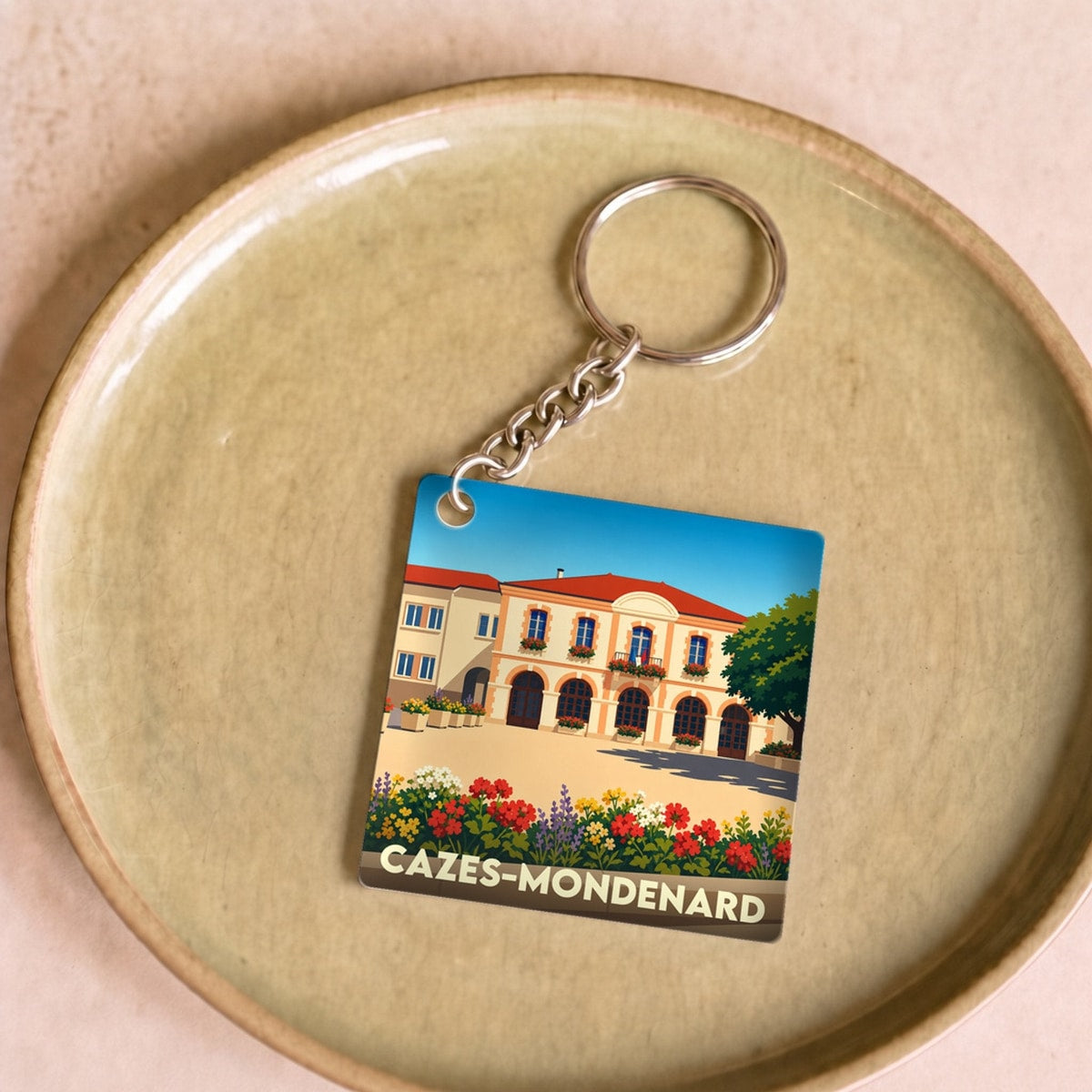 Porte-clés souvenir de la ville de Cazes-Mondenard avec une illustration stylisée de sa mairie.