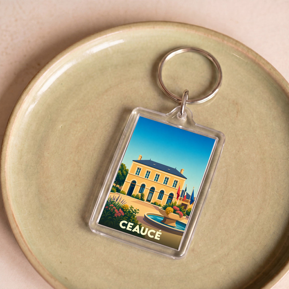 Porte-clés souvenir de la ville de Ceaucé avec une illustration stylisée de sa mairie.