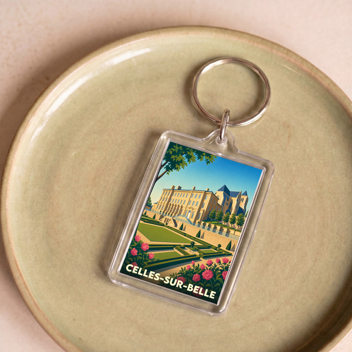 Porte-clés souvenir de la ville de Celles-sur-Belle avec une illustration stylisée de son abbaye et de ses jardins.