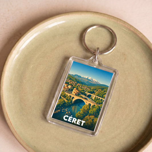Porte-clés souvenir de la ville de Céret avec une illustration stylisée de son pont et des montagnes.