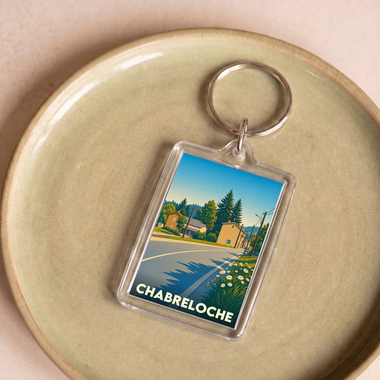 Porte-clés souvenir de la ville de Chabreloche avec une illustration stylisée d'un paysage urbain.