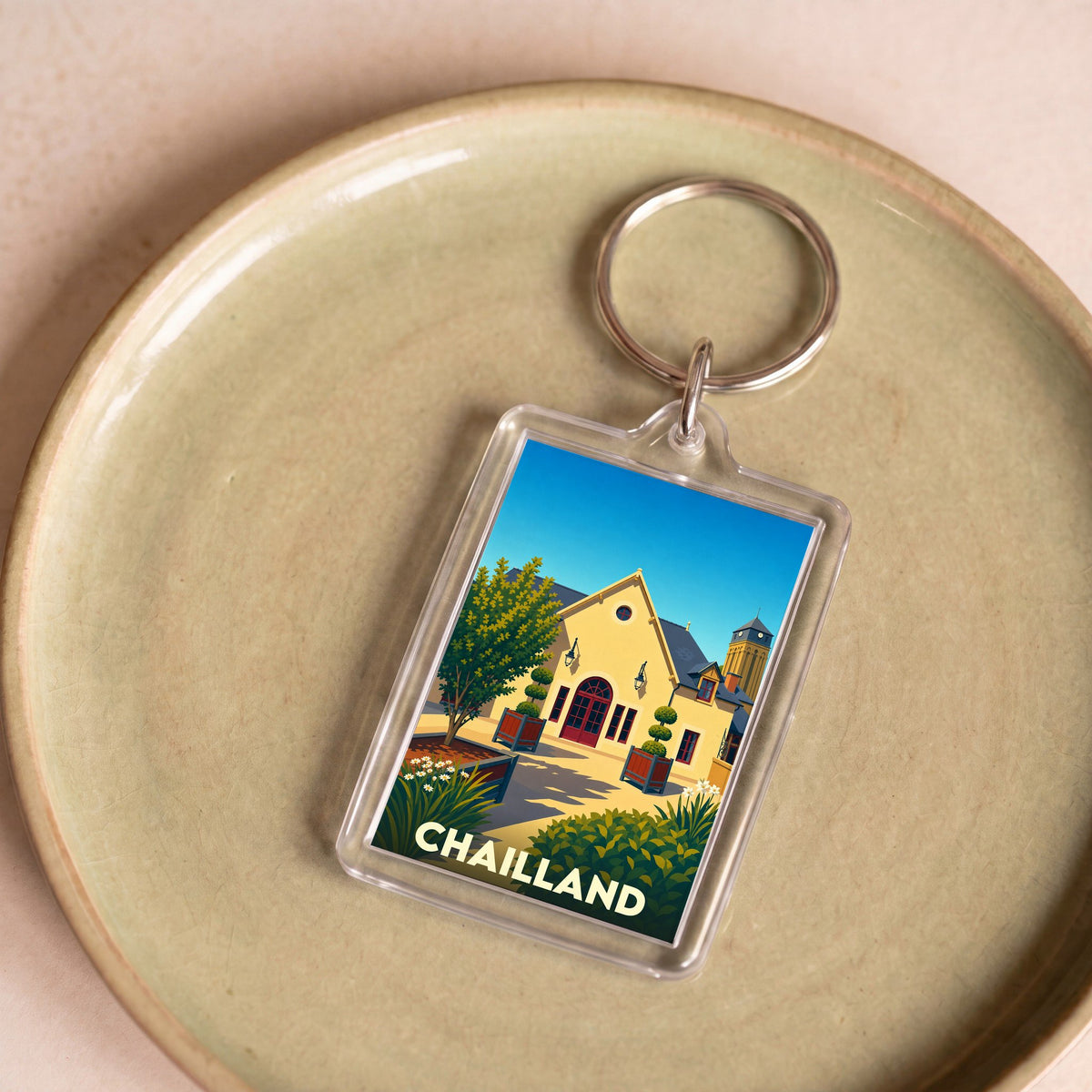 Porte-clés souvenir de la ville de Chailland avec une illustration stylisée.