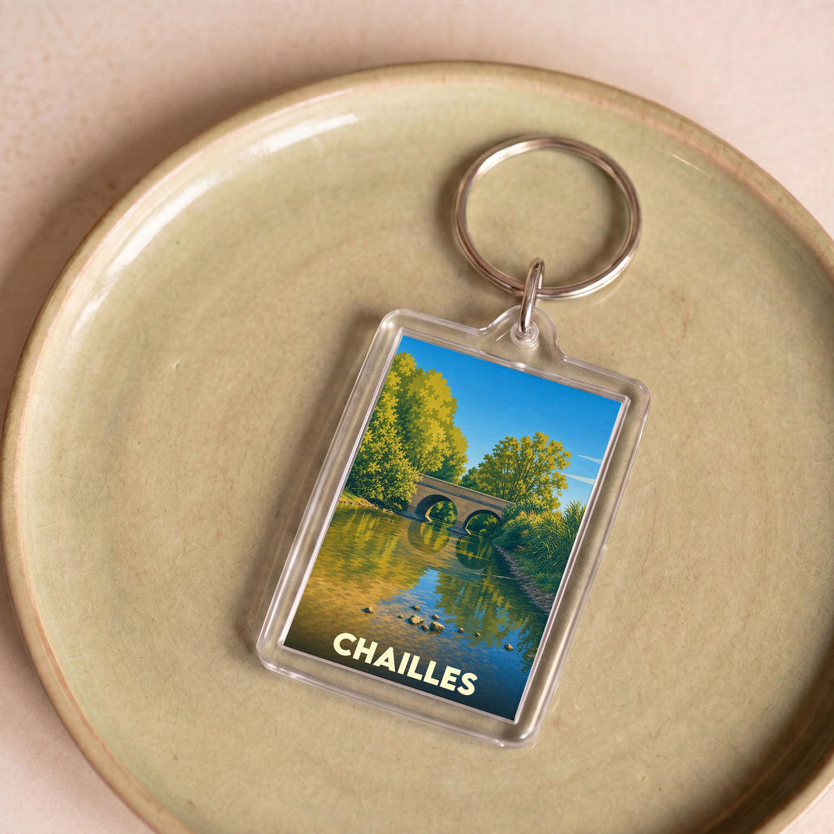 Porte-clés souvenir de la ville de Chailles illustrant un pont de pierre se reflétant dans l'eau.