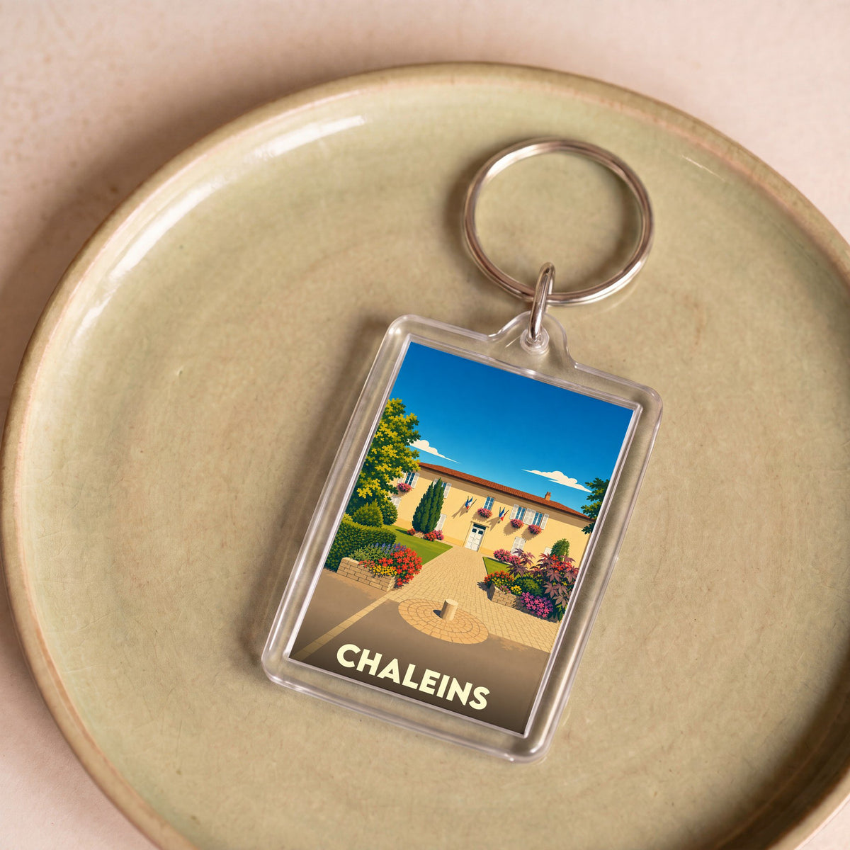 Porte-clés souvenir de la ville de Chaleins avec une illustration stylisée de sa mairie fleurie.