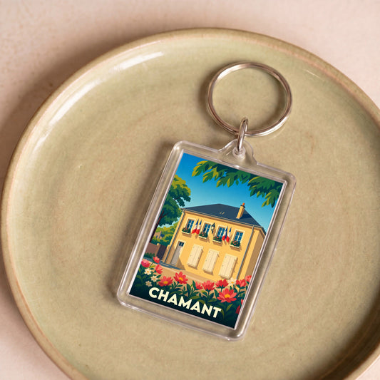 Porte-clés souvenir de la ville de Chamant avec une illustration stylisée d'une maison fleurie.