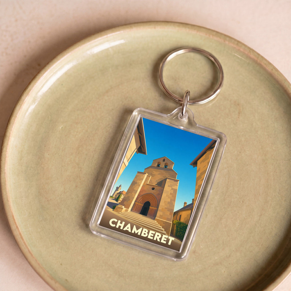 Porte-clés souvenir de la ville de Chamberet avec une illustration stylisée de son église.