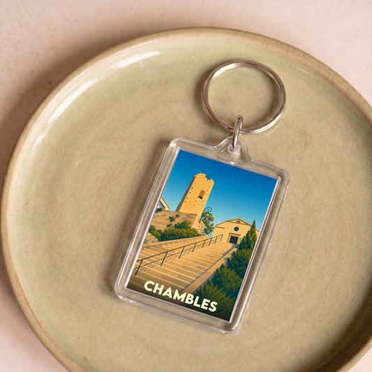 Porte-clés souvenir de la ville de Chambles avec une illustration stylisée de son patrimoine.