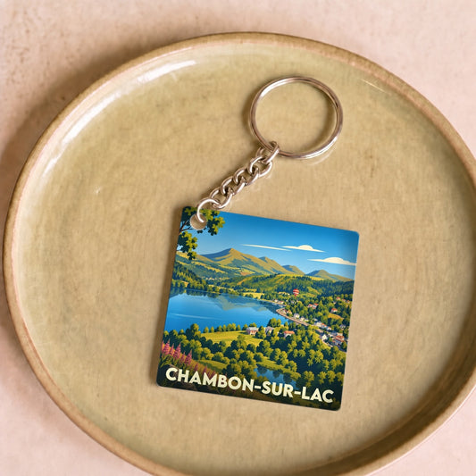 Porte-clés souvenir de la ville de Chambon-sur-Lac avec une illustration stylisée d'un paysage de montagne et de lac.