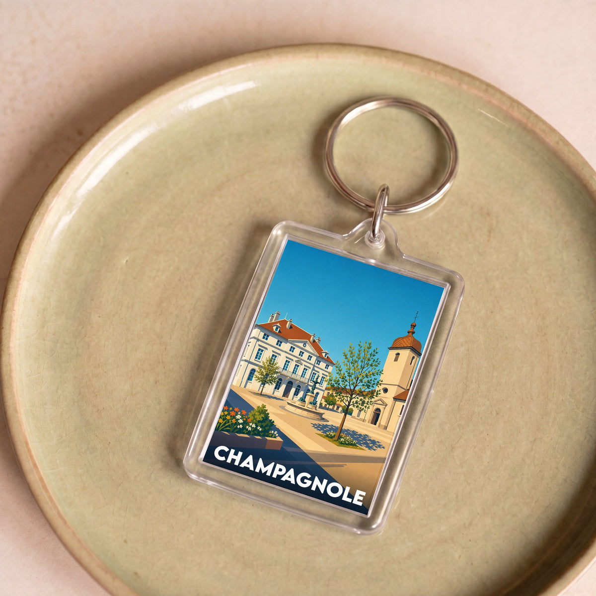 Porte-clés souvenir de la ville de Champagnole avec une illustration stylisée de son architecture.