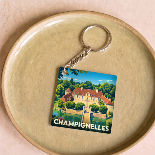 Porte-clés souvenir de la ville de Champignelles avec une illustration stylisée d'un château entouré d'eau.
