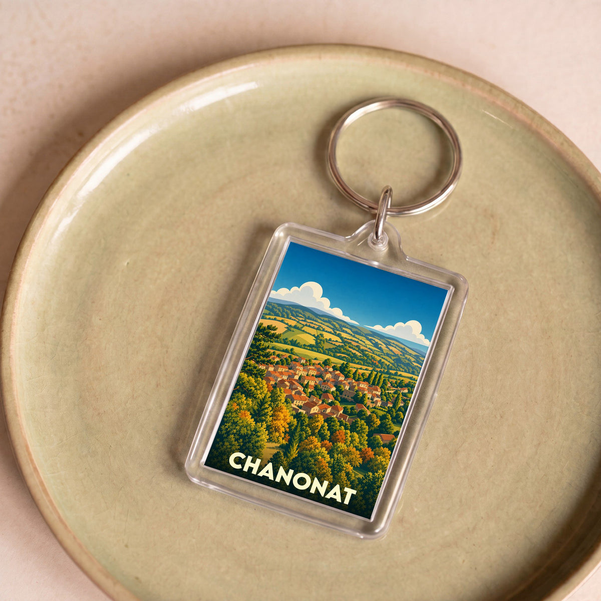 Porte-clés souvenir de la ville de Chanonat avec une illustration stylisée de son paysage vallonné.