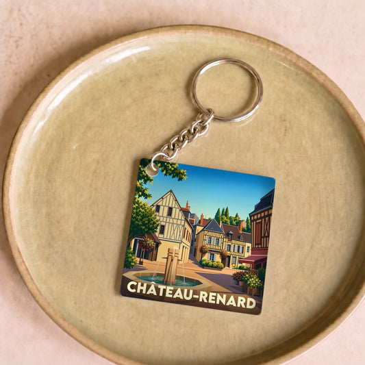 Porte-clés souvenir de la ville de Château-Renard avec une illustration stylisée d'une place animée.