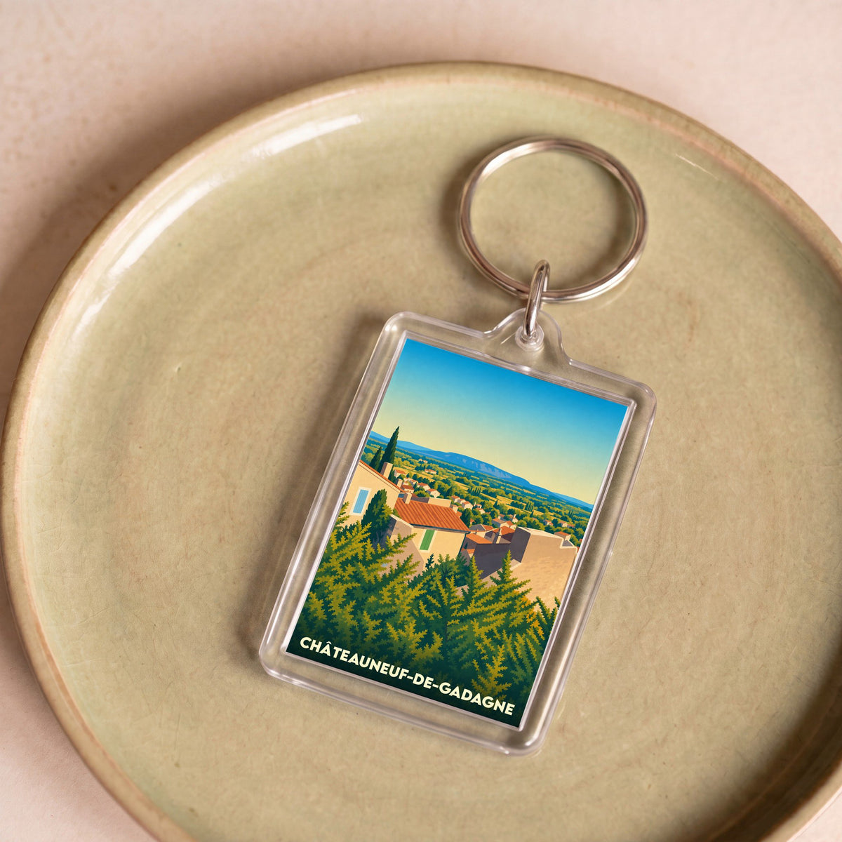 Porte-clés souvenir de la ville de Châteauneuf-de-Gadagne avec une illustration stylisée de son paysage.