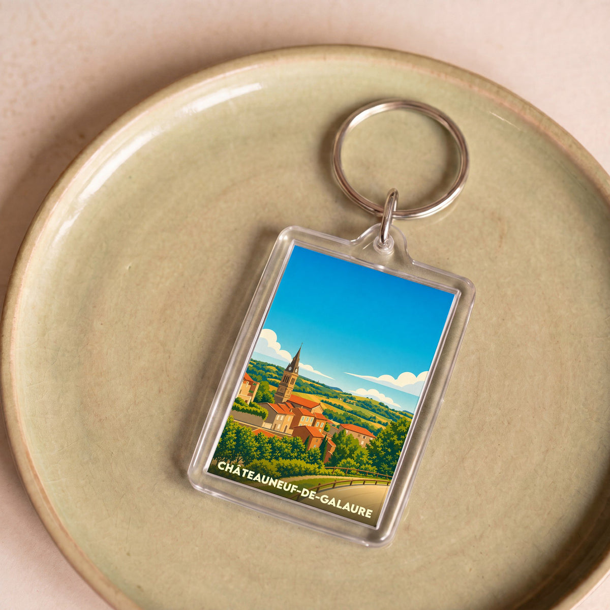 Porte-clés souvenir de la ville de Châteauneuf-de-Galaure avec une illustration stylisée du village.