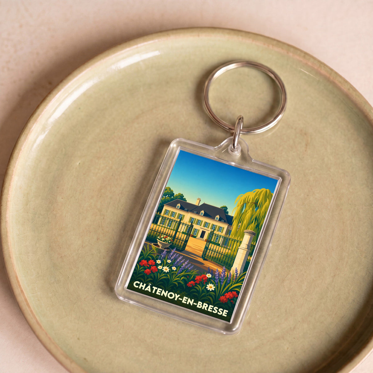 Porte-clés souvenir de la ville de Châtenoy-en-Bresse avec une illustration stylisée d'une demeure bourguignonne et son jardin fleuri.
