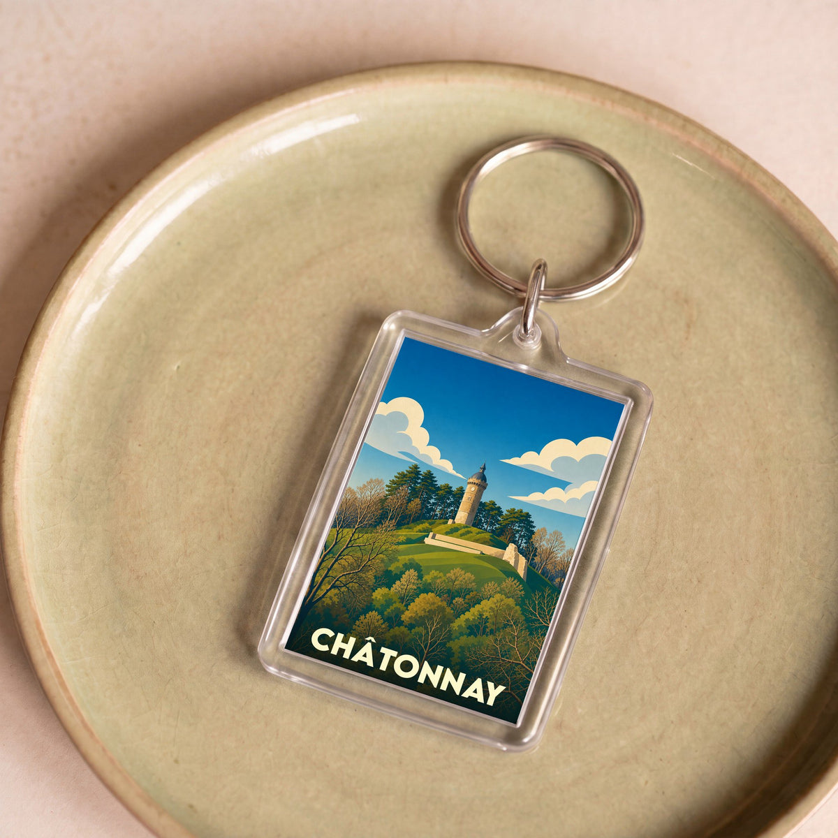 Porte-clés souvenir de la ville de Châtonnay avec une illustration stylisée d'une tour sur une colline boisée.