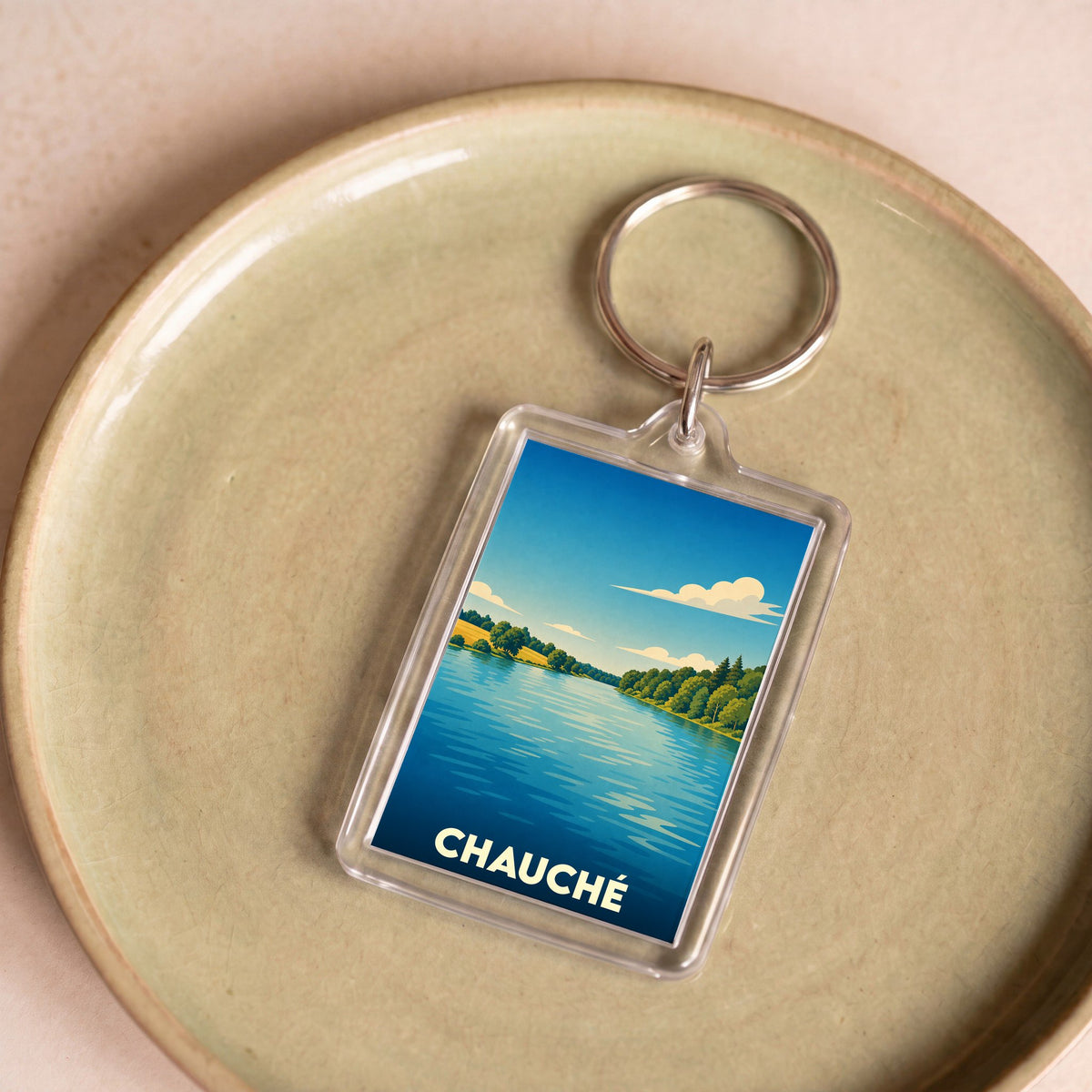 Porte-clés souvenir de la ville de Chauché avec une illustration stylisée d'un paysage lacustre.