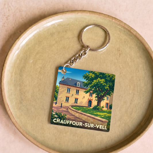 Porte-clés souvenir de la ville de Chauffour-sur-Vell avec une illustration stylisée d'un bâtiment historique et d'un arbre.