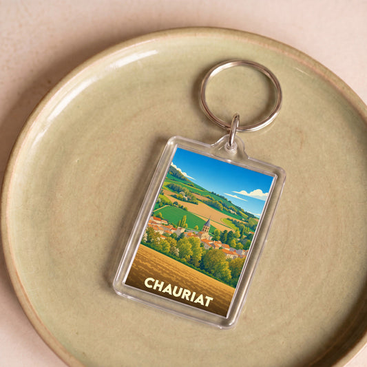 Porte-clés souvenir de la ville de Chauriat avec une illustration stylisée de son paysage champêtre.