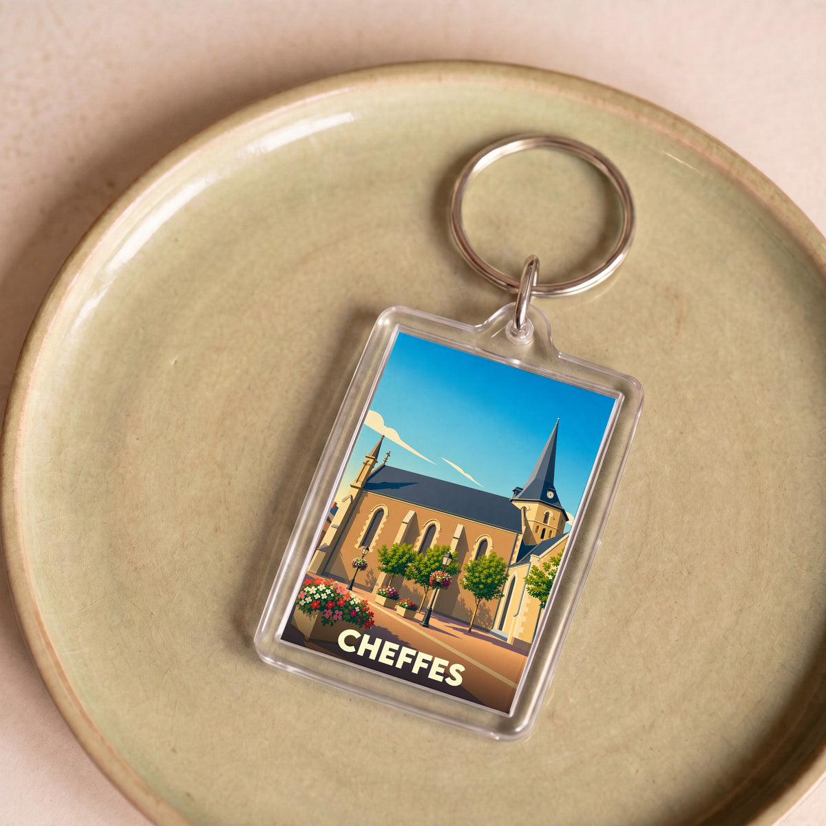 Porte-clés souvenir de la ville de Cheffes avec une illustration stylisée de son église.