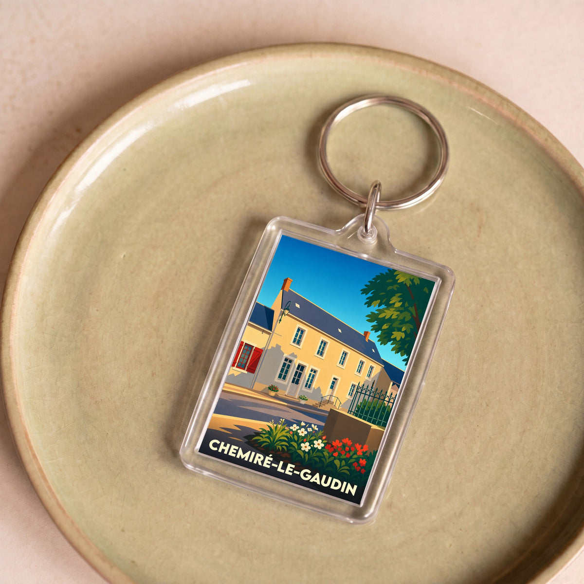 Porte-clés souvenir de la ville de Chemiré-le-Gaudin avec une illustration stylisée d'une maison ancienne.
