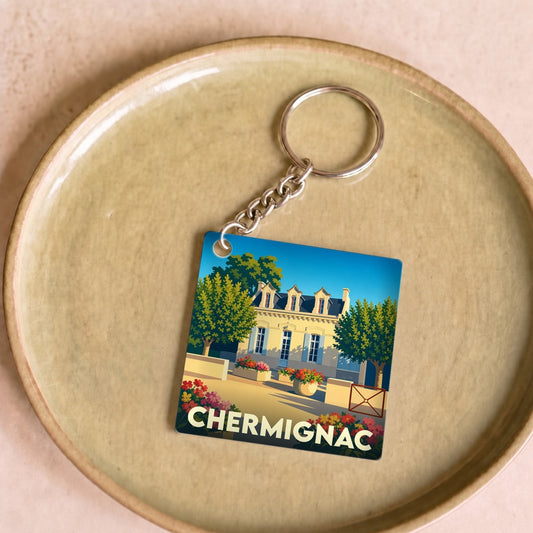 Porte-clés souvenir de la ville de Chermignac avec une illustration stylisée d'une demeure fleurie.
