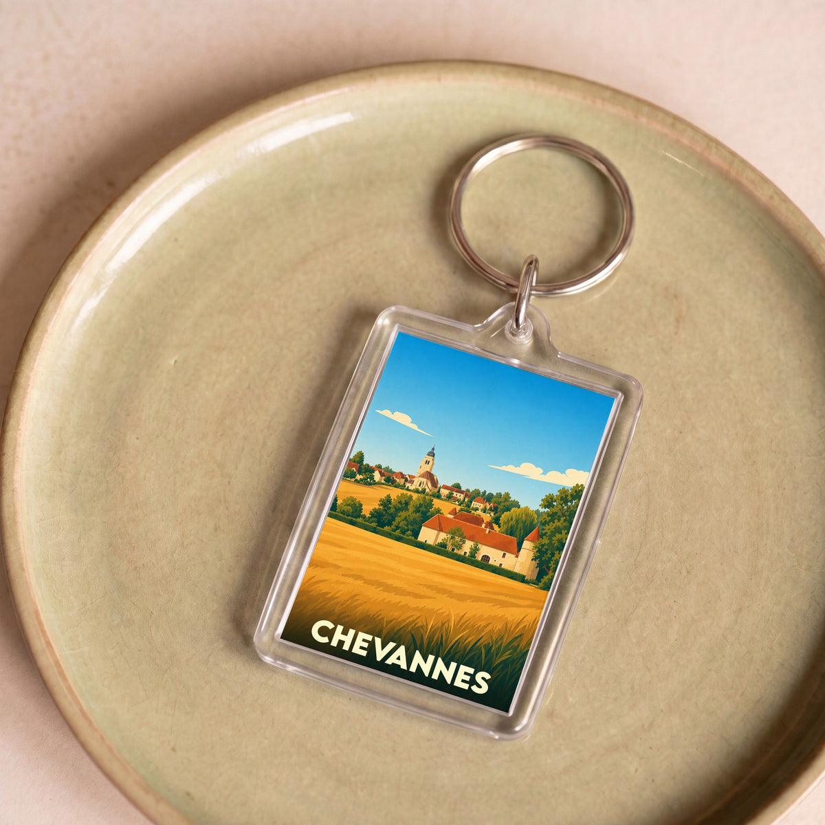 Porte-clés souvenir de la ville de Chevannes avec une illustration stylisée de son paysage et de son église.