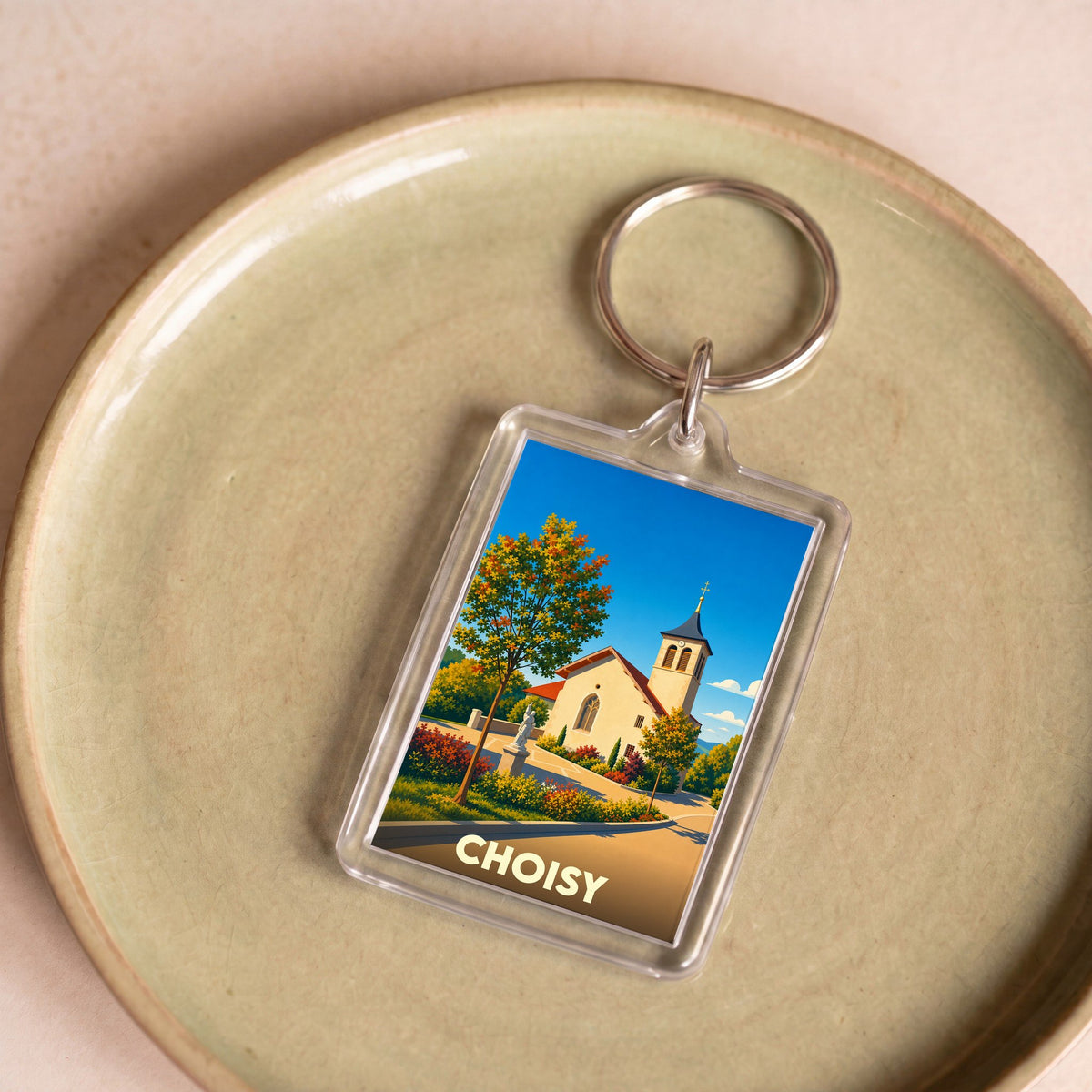 Porte-clés souvenir de la ville de Choisy avec une illustration stylisée de son église sous un ciel bleu.
