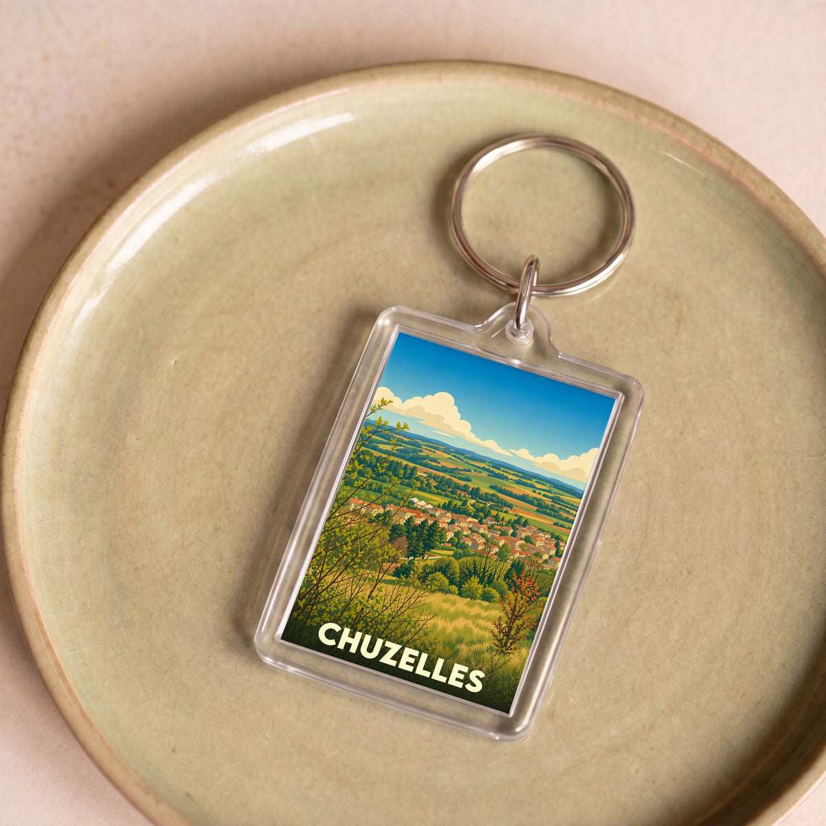 Porte-clés souvenir de la ville de Chuzelles avec une illustration stylisée de son paysage.