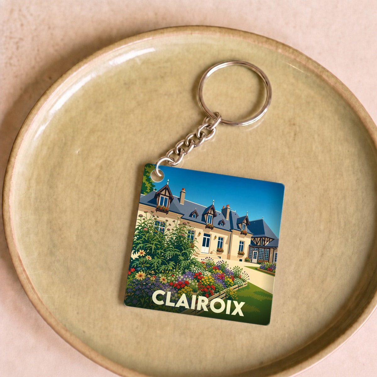 Porte-clés souvenir de la ville de Clairoix avec une illustration stylisée d'un manoir fleuri.