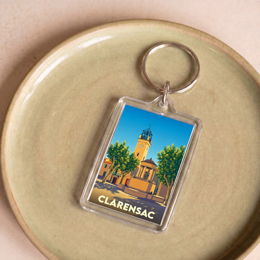 Porte-clés souvenir de la ville de Clarensac avec une illustration stylisée d'une place ensoleillée.
