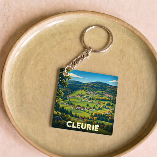 Porte-clés souvenir de la ville de Cleurie avec une illustration stylisée d'un paysage montagneux.