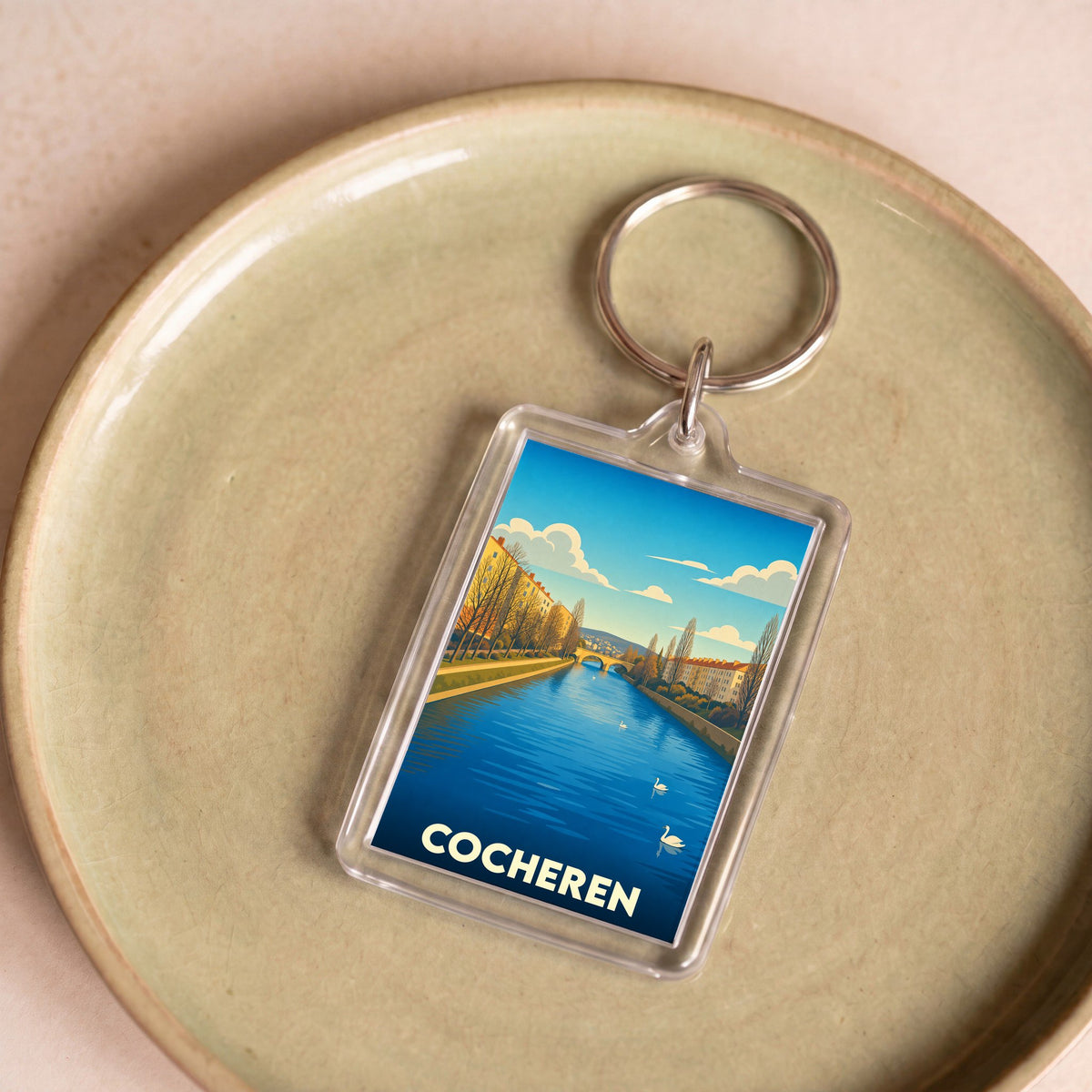 Porte-clés souvenir de la ville de Cocheren avec une illustration stylisée d'un canal et de cygnes.