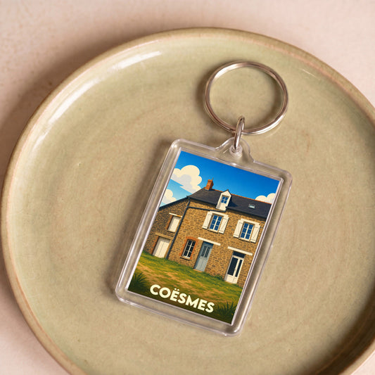 Porte-clés souvenir de la ville de Coësmes avec une illustration stylisée d'une maison traditionnelle.