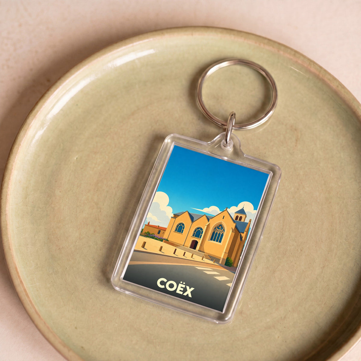 Porte-clés souvenir de la ville de Coëx avec une illustration stylisée de son église.