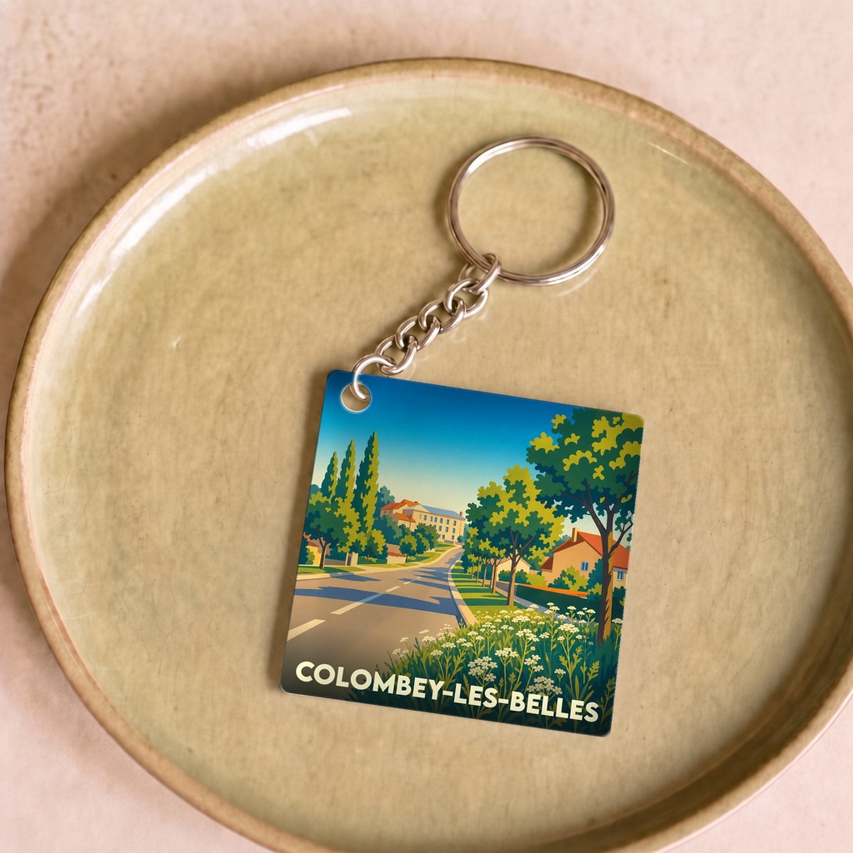 Porte-clés souvenir de la ville de Colombey-les-Belles avec une illustration stylisée d'un paysage urbain verdoyant.