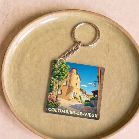 Porte-clés souvenir de la ville de Colombier-le-Vieux avec une illustration stylisée d'une rue pittoresque.