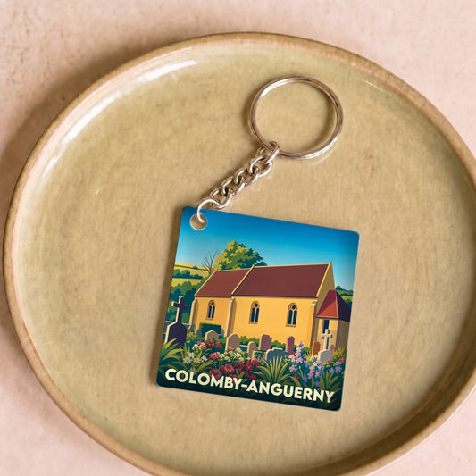 Porte-clés souvenir de la ville de Colomby-Anguerny avec une illustration stylisée de son église et de son cimetière fleuri.