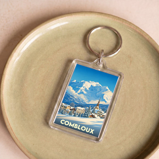 Porte-clés souvenir de la ville de Combloux avec une illustration stylisée de montagne enneigée.