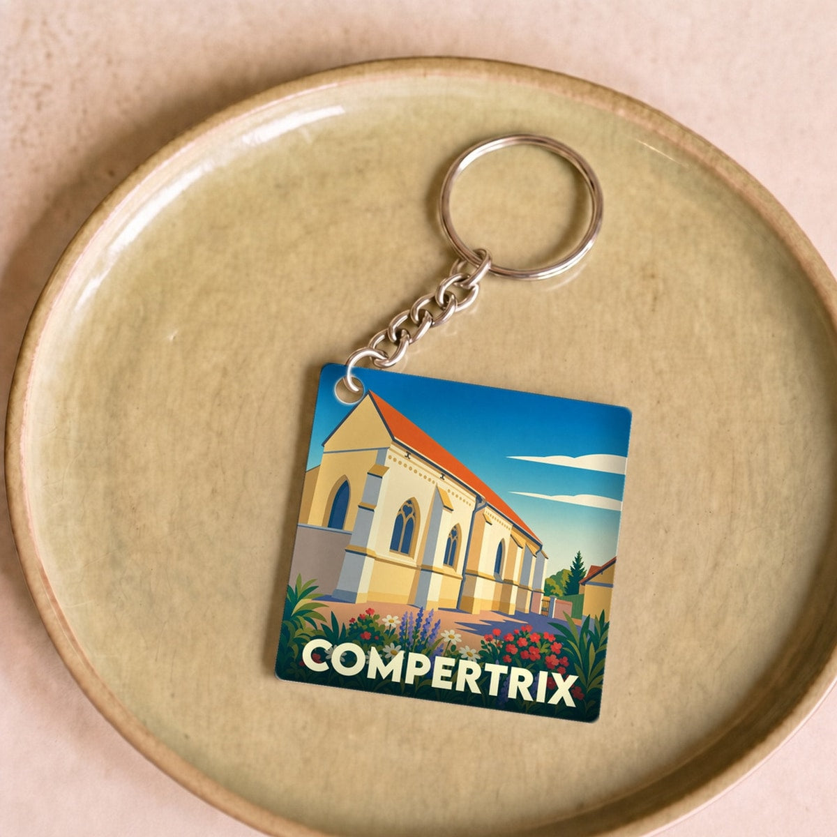 Porte-clés souvenir de la ville de Compertrix avec une illustration stylisée de son église.