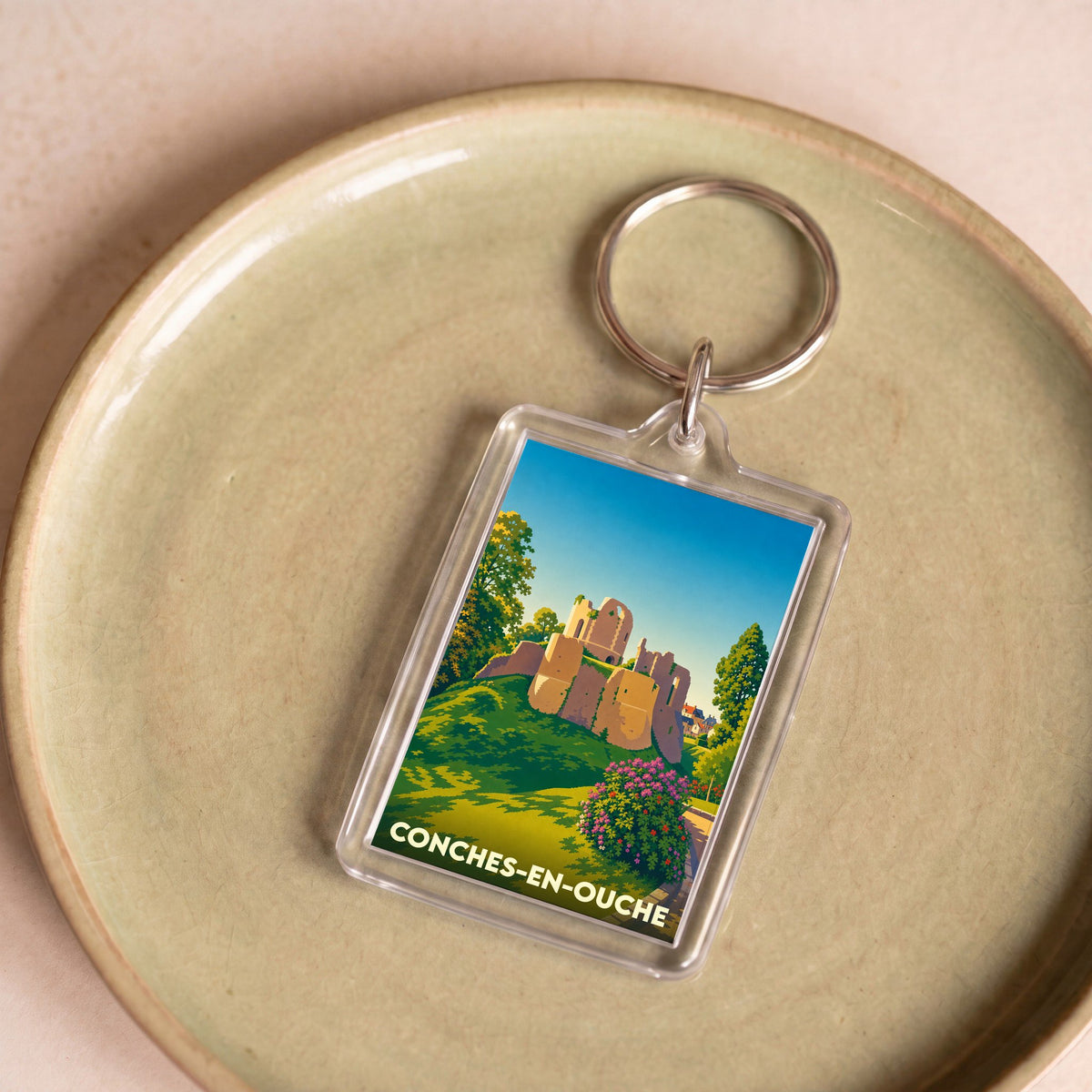 Porte-clés souvenir de la ville de Conches-en-Ouche avec une illustration stylisée de son château médiéval.