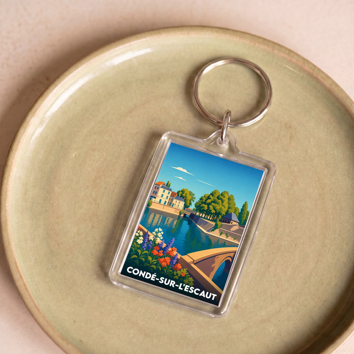 Porte-clés souvenir de la ville de Condé-sur-l'Escaut avec une illustration stylisée d'un paysage urbain au bord de l'eau.
