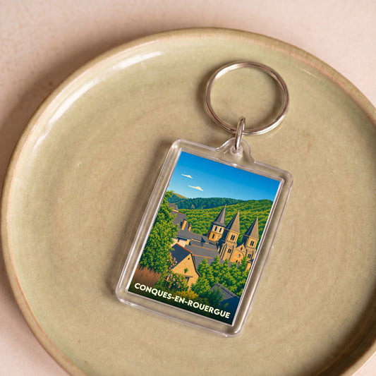 Porte-clés souvenir de la ville de Conques-en-Rouergue avec une illustration stylisée de son église abbatiale.