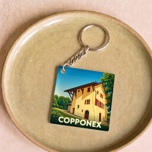 Porte-clés souvenir de la ville de Copponex avec une illustration stylisée d'un bâtiment traditionnel.