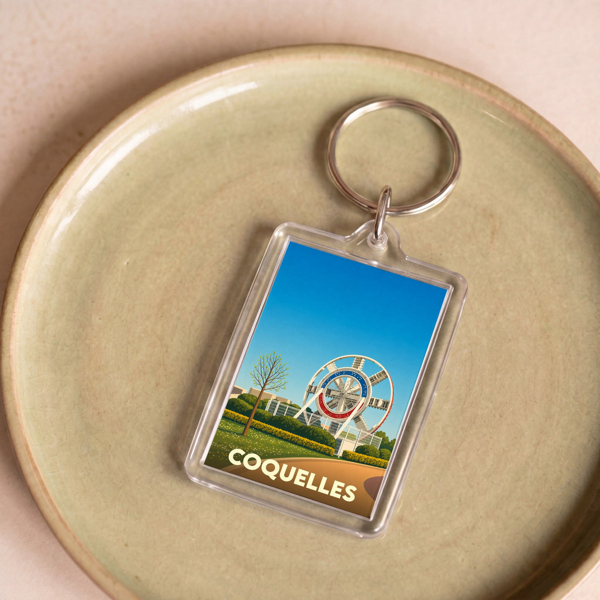 Porte-clés souvenir de la ville de Coquelles avec une illustration stylisée d'un monument local.