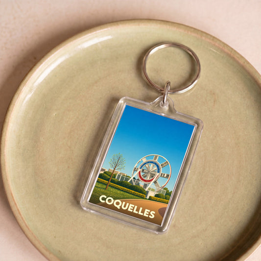 Porte-clés souvenir de la ville de Coquelles avec une illustration stylisée d'un monument local.