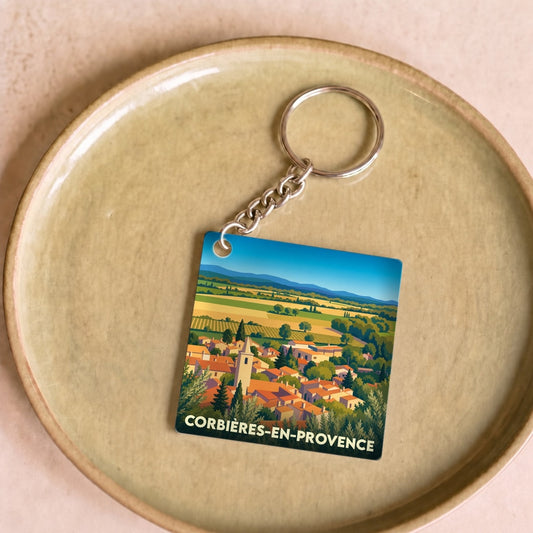 Porte-clés souvenir de Corbières-en-Provence avec une illustration stylisée du village et de ses paysages.