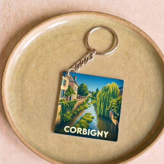 Porte-clés souvenir de la ville de Corbigny avec une illustration stylisée d'un canal bordé de maisons et de végétation.