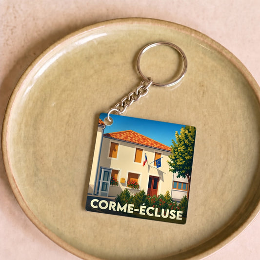 Porte-clés souvenir de la ville de Corme-Écluse avec une illustration stylisée de sa mairie.