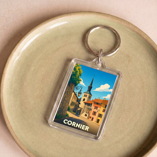 Porte-clés souvenir de la ville de Cornier avec une illustration stylisée d'une rue pittoresque et de son clocher.